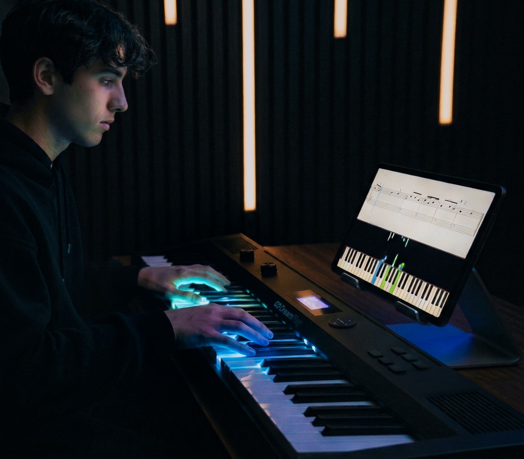 Pianist playing DreamPlay One with LED-lit keys and Learn app on tablet